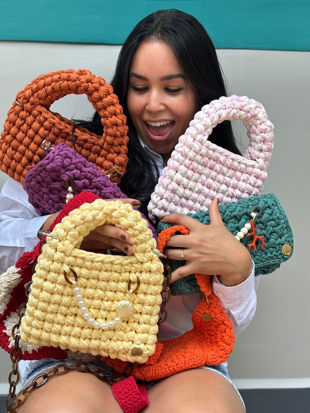 Criadora do ateliê Balm for Home segurando bolsas de crochê coloridas